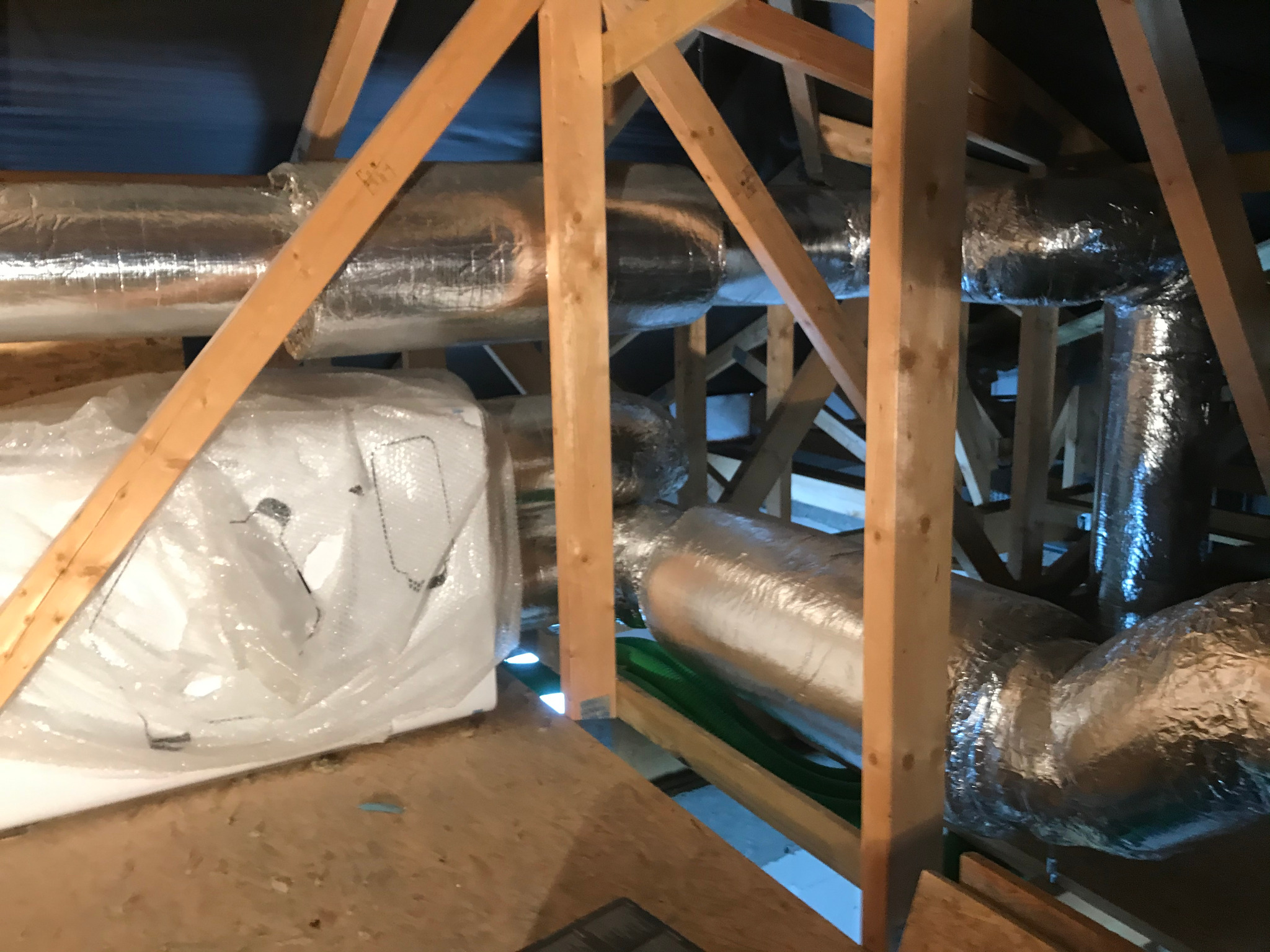 System przewodów wentylacyjnych w izolacji aluminiowej, zamontowany na drewnianej konstrukcji poddasza.