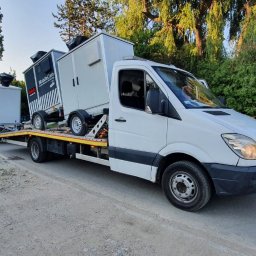 Laweta Warszawa - Biała laweta Mercedes-Benz z dwoma przyczepami z kontenerami MobileCam na platformie, widok z boku na tle zieleni.