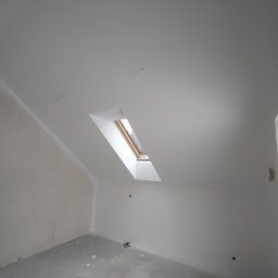 NUMERNABIS PROJEKTY SPÓŁKA Z OGRANICZONĄ ODPOWIEDZIALNOŚCIĄ - Poddasze z oknem dachowym po nałożeniu gładzi, widoczne niedoskonałości na podłodze i ścianach przed dalszym wykończeniem.