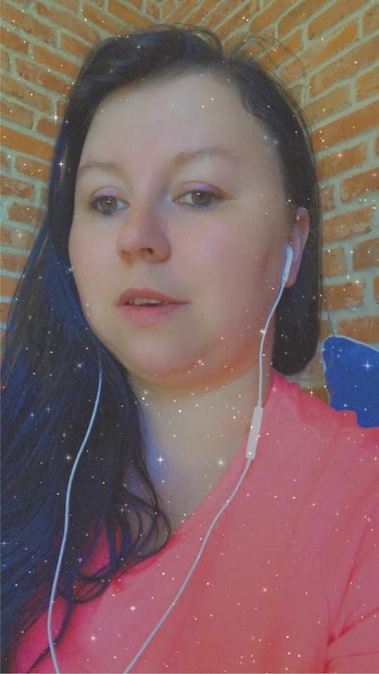 Portret kobiety w różowej bluzce z słuchawkami na tle ceglanej ściany, z efektem błyszczących drobinek.