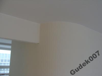 Świeżo pomalowane wnętrze z zaokrąglonym narożnikiem ściany i widocznym fragmentem okna. Na ścianie widoczny znak wodny 'Gudek007'.