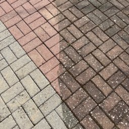 Dominik Parniak - Częściowo wyczyszczona kostka brukowa ułożona w jodełkę, widoczna różnica w kolorze między czystą a brudną powierzchnią.