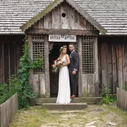 Para młoda pozuje na tle starej, drewnianej apteki z kwiatami i wiankiem na głowie