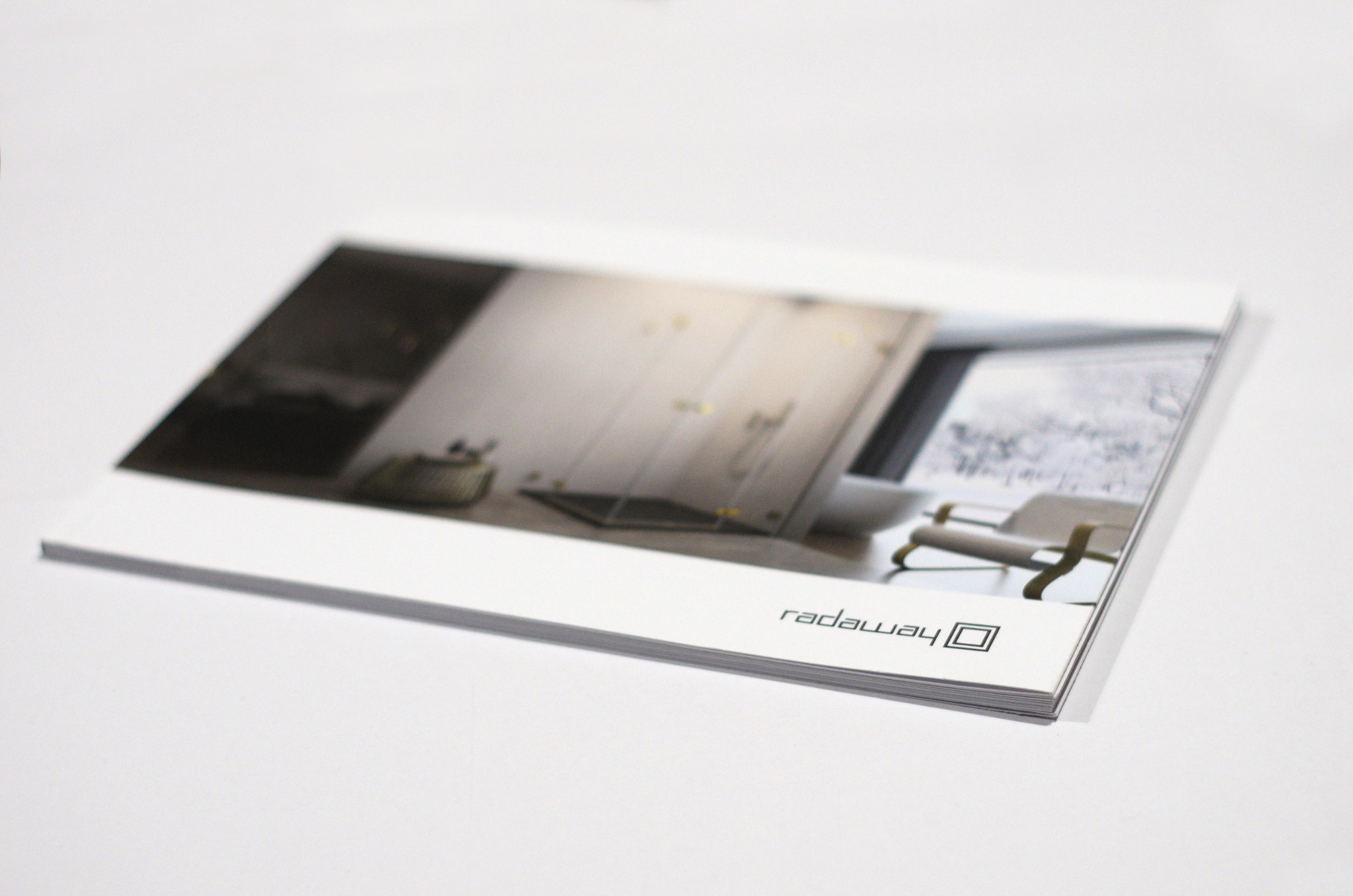 Stos ulotek reklamowych z widocznym zdjęciem łazienki i logo firmy Radaway