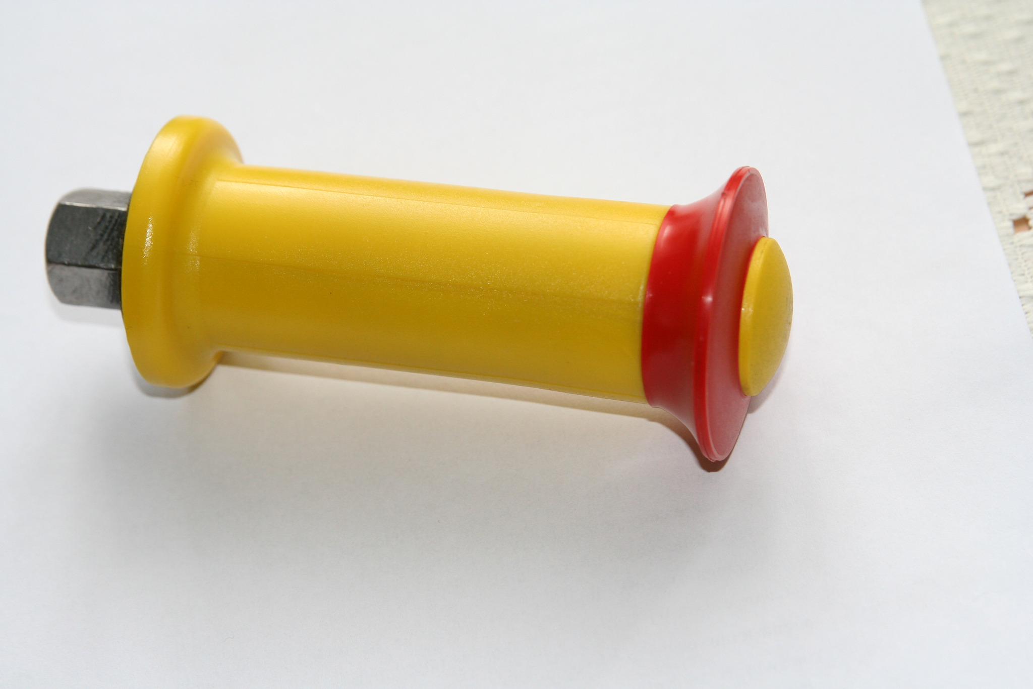 Żółto-czerwony uchwyt z metalową śrubą na białym tle, element placu zabaw.