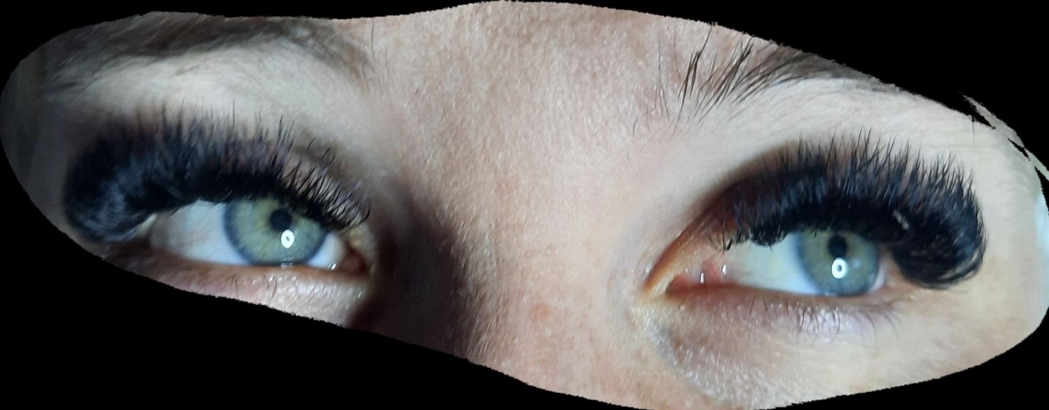 Zbliżenie na oczy z przedłużonymi, bardzo gęstymi, czarnymi rzęsami; widoczne zielone tęczówki i naturalne brwi.