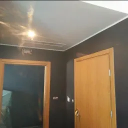 Ciemnoszary pokój po malowaniu z widocznym fragmentem sufitu napinanego i otwartymi drewnianymi drzwiami, widoczna instalacja na suficie.