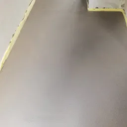 Świeżo wylana, gładka posadzka jastrychowa, zabezpieczona taśmą piankową przy ścianach, przygotowana do dalszych prac wykończeniowych.