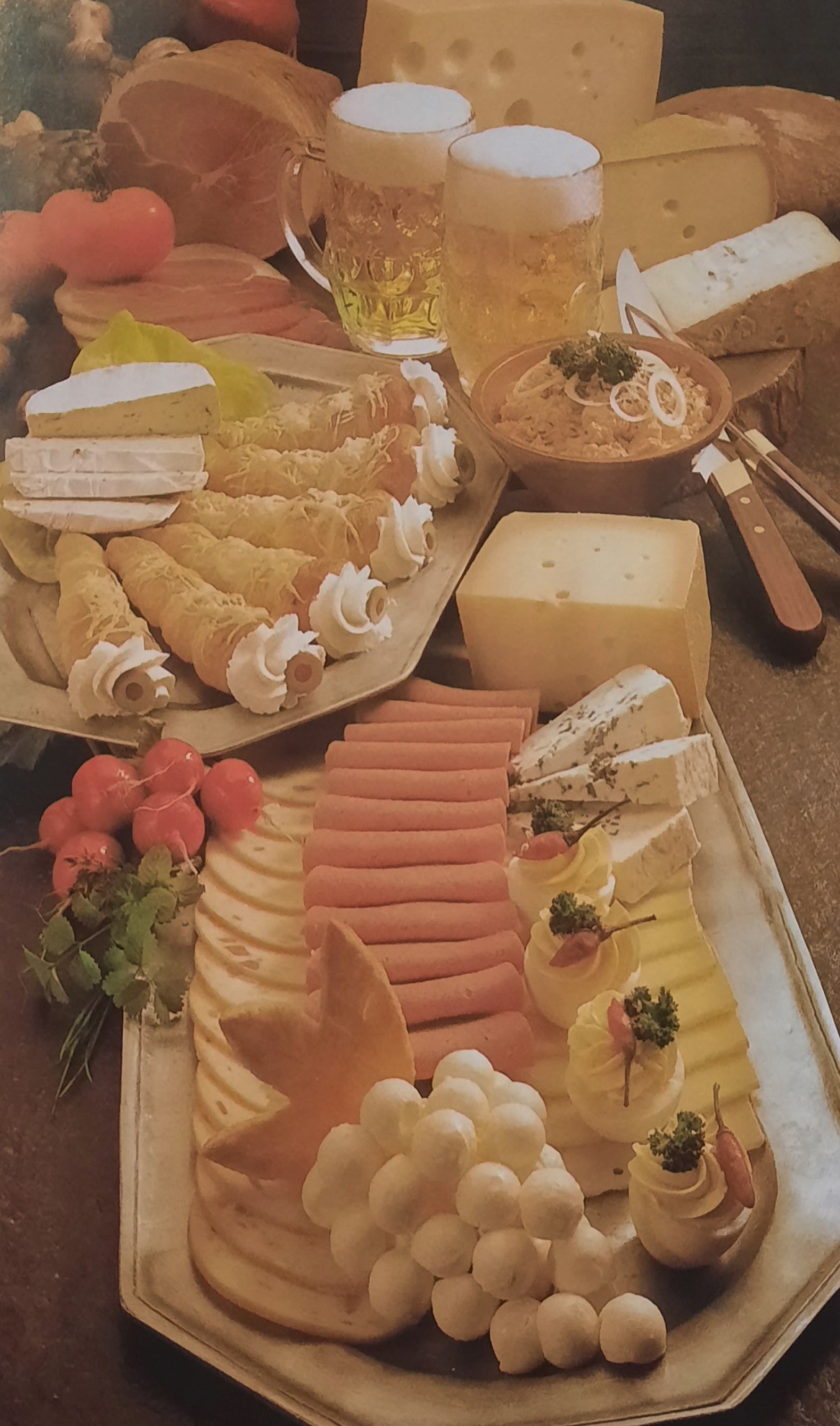 Bogato zastawiony stół z różnorodnymi serami, wędlinami, sałatkami, piwem i dekoracjami, idealny na przyjęcie.