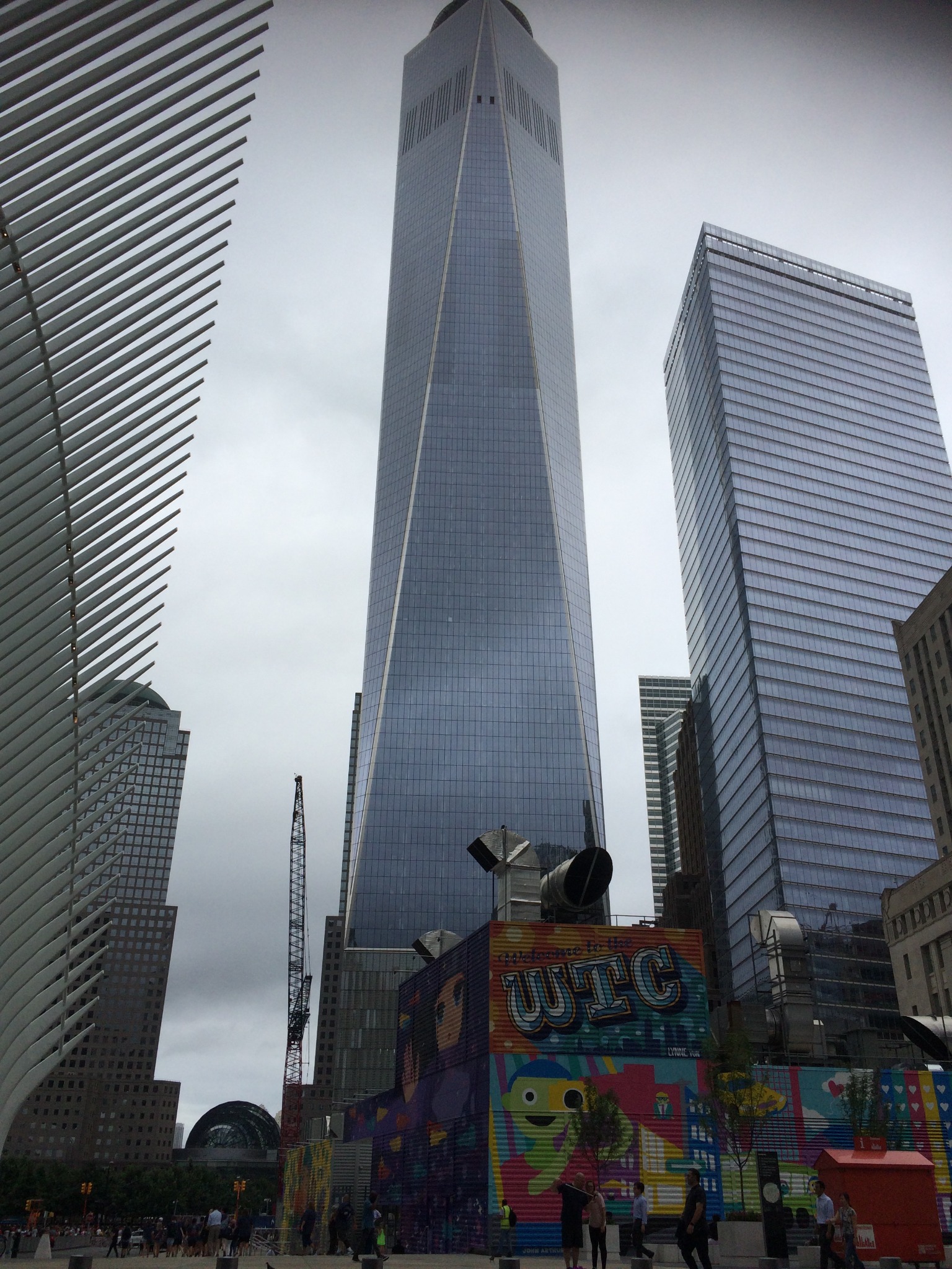 Nowoczesna architektura miejska: drapacze chmur, konstrukcja z białych żeber oraz kolorowe murale w strefie World Trade Center na tle pochmurnego nieba.