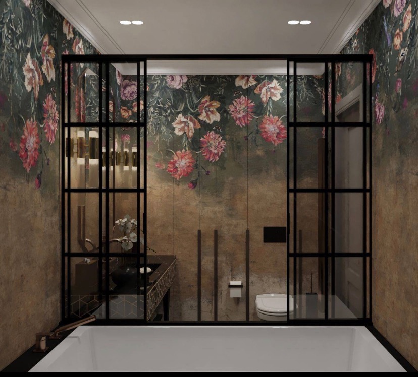 Nowoczesna łazienka z wanną, kabiną prysznicową typu walk-in z czarnymi profilami, umywalką na blacie z dekoracyjnym wzorem i ścianami pokrytymi tapetą w kwiaty.
