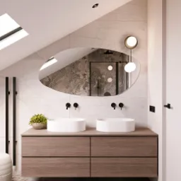 Nowoczesna łazienka na poddaszu z podwójną umywalką nablatową, owalnym lustrem odbijającym kabinę prysznicową i marmurową okładziną ścian.