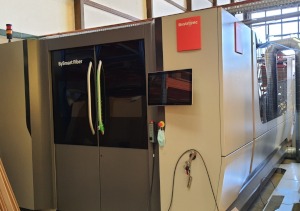 Nowoczesna maszyna do cięcia laserowego stali Bystronic Fiber z panelem sterowania i czerwonym logo producenta, widoczna w hali produkcyjnej.