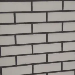 Ściana z białych, prostokątnych cegieł z ciemnoszarą fugą, ułożonych w regularnym wzorze.