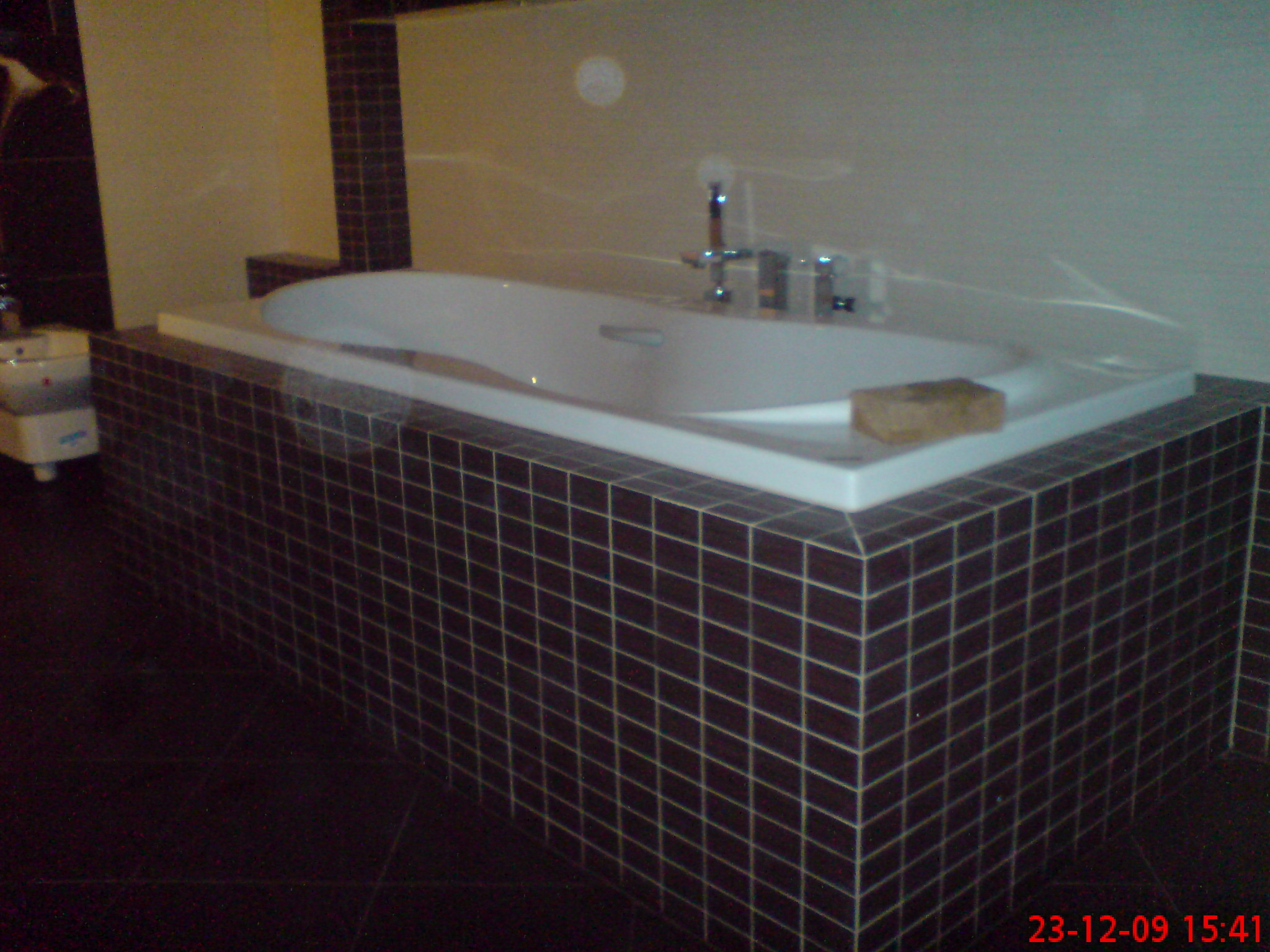 Obudowana brązowymi płytkami wanna z hydromasażem i baterią, widoczna data na zdjęciu.