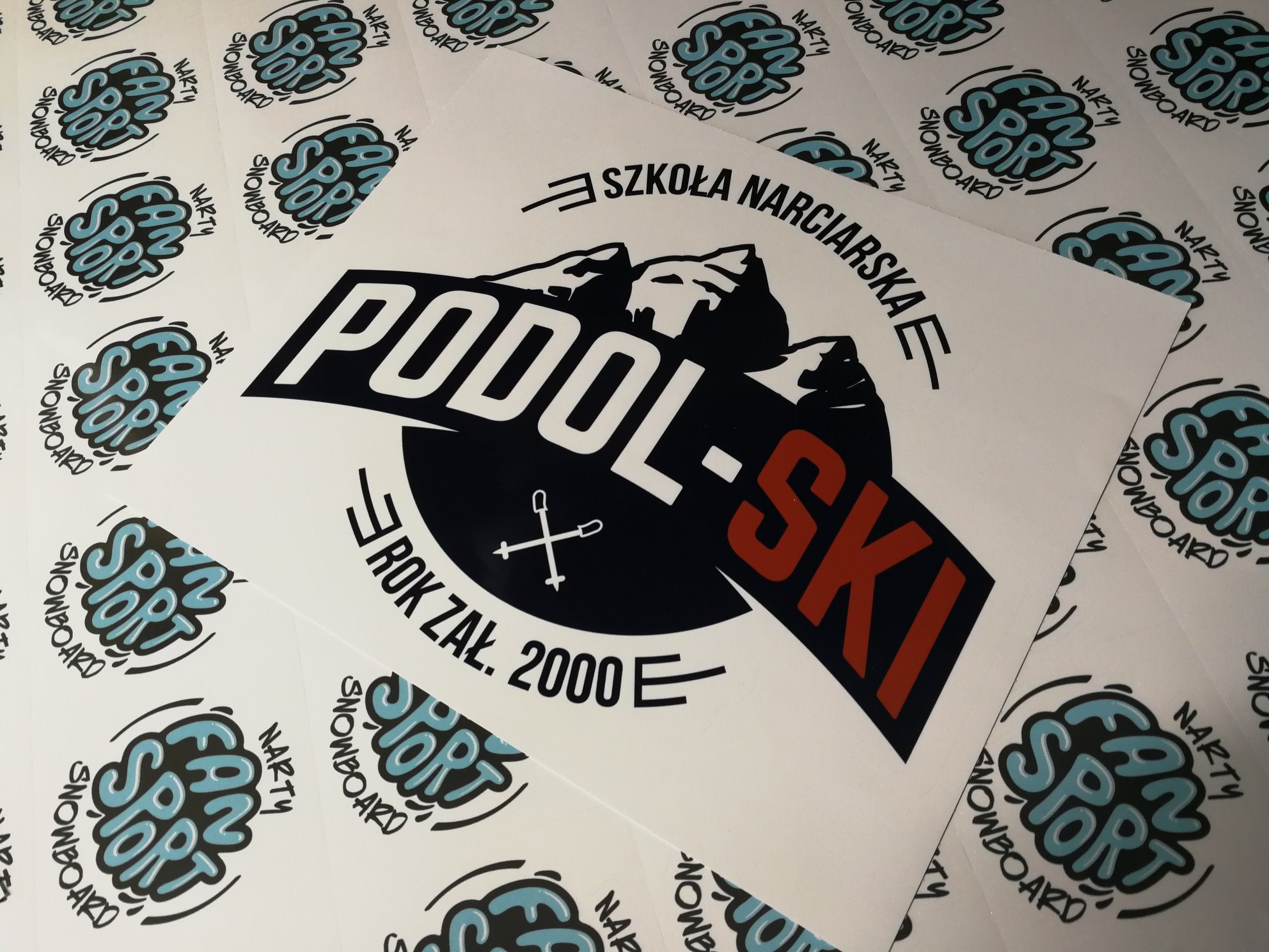 Arkusze samoprzylepne z logo szkoły narciarskiej Podol-Ski oraz logotypem Fan Sport Narty Snowboard, gotowe do odklejenia.