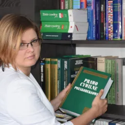 Portret kobiety w okularach, trzymającej otwartą książkę 'Prawo cywilne pozakodeksowe' na tle regału z książkami prawniczymi.