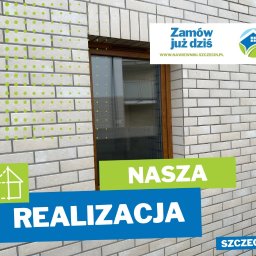 Nawiewniki - Szczecin - Elewacja budynku z oknem, ozdobiona naklejkami reklamowymi firmy z branży instalacyjnej, prezentująca ukończoną realizację w Szczecinie.