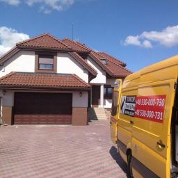 Techniczne Usługi Natryskowe - Dwukondygnacyjny dom z brązową bramą garażową i czerwoną dachówką, z żółtym samochodem serwisowym z naklejkami z numerem telefonu.