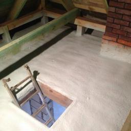 Techniczne Usługi Natryskowe - Poddasze po ociepleniu pianką PUR: drewniana konstrukcja, ceglany komin, drabina w otworze. Widok z góry ukazuje równomierną warstwę izolacji.