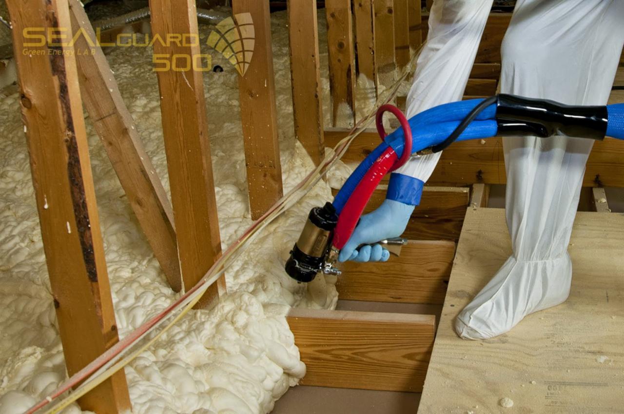 Aplikacja pianki PUR w przestrzeni poddasza. Widoczne drewniane elementy konstrukcyjne i osoba w kombinezonie ochronnym, aplikująca pianę za pomocą specjalistycznego sprzętu.