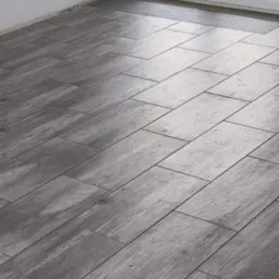 Ułożone pod kątem płytki podłogowe imitujące drewno w odcieniach szarości, widok na białe okno balkonowe z widokiem na zewnątrz.