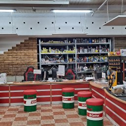 Solar Systems B.C. Łukasz Bęben - Wnętrze sklepu z częściami samochodowymi i olejami, widoczne regały z produktami Motul i Castrol, stanowisko obsługi klienta z krzesłami w kształcie beczek Castrol.