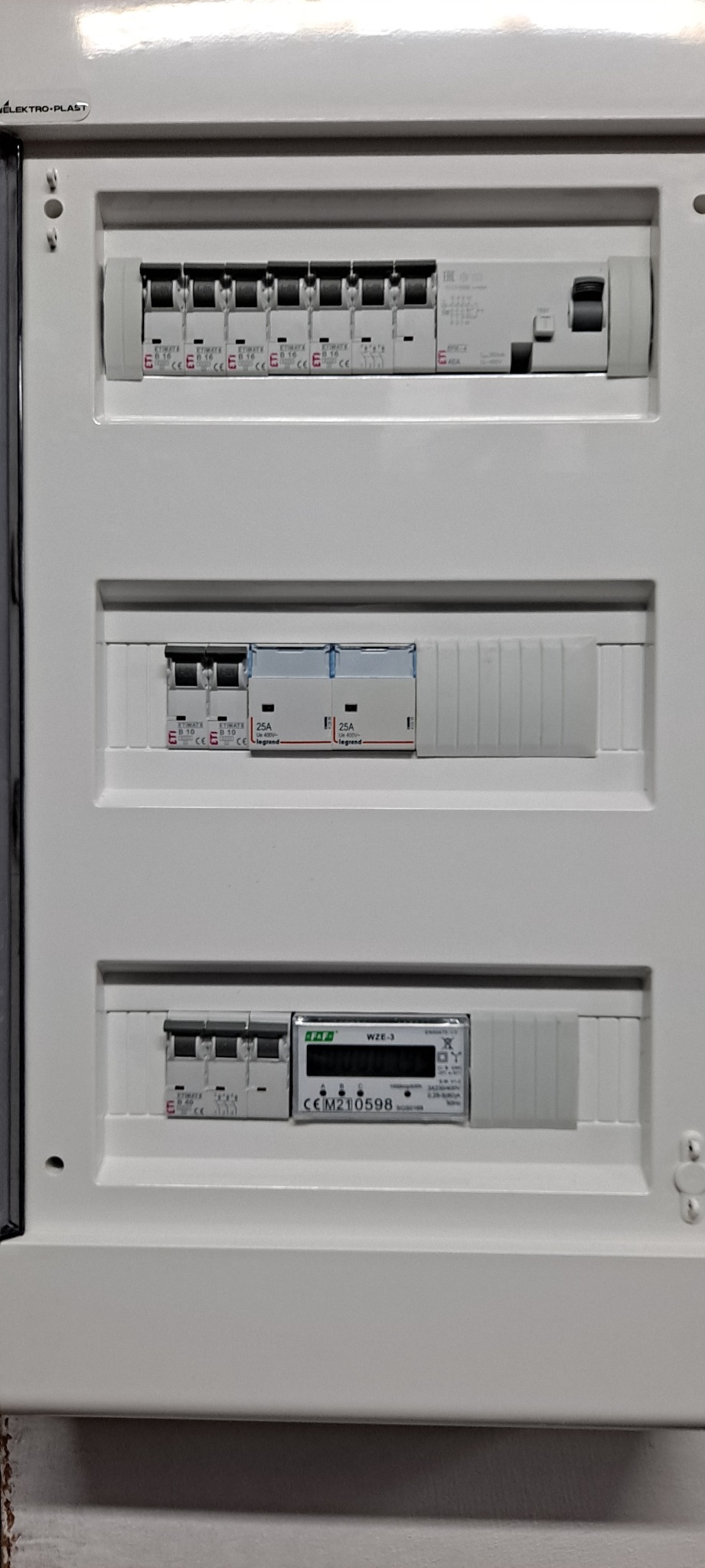 Rozdzielnica elektryczna z zainstalowanymi bezpiecznikami ETIMAT i licznikiem energii WZE-3, widoczne oznaczenia i parametry urządzeń.
