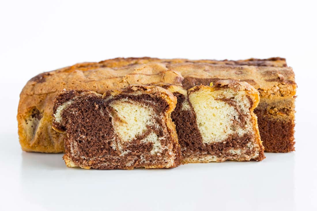 Krojony babkowy keks marmurkowy z wyraźnymi warstwami czekolady i wanilii, ukazujący nieregularny wzór w przekroju, na białym tle.