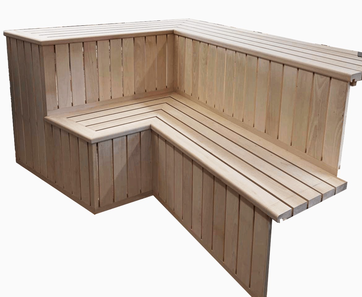 Wnętrze sauny z jasnego drewna, przedstawiające narożne ławki z oparciami, wykonane z pionowych desek z przerwami.