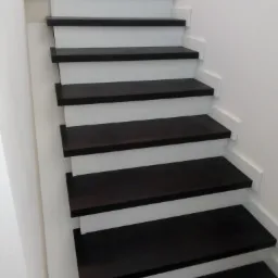 Nowoczesne schody z ciemnego drewna i białymi podstopnicami, minimalistyczny design.