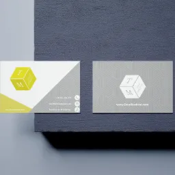 Dwie wizytówki firmy Total Medical na teksturowanym tle, jedna z żółto-białym designem, druga w odcieniach szarości, obie z logo w kształcie sześcianu z literami T i M.