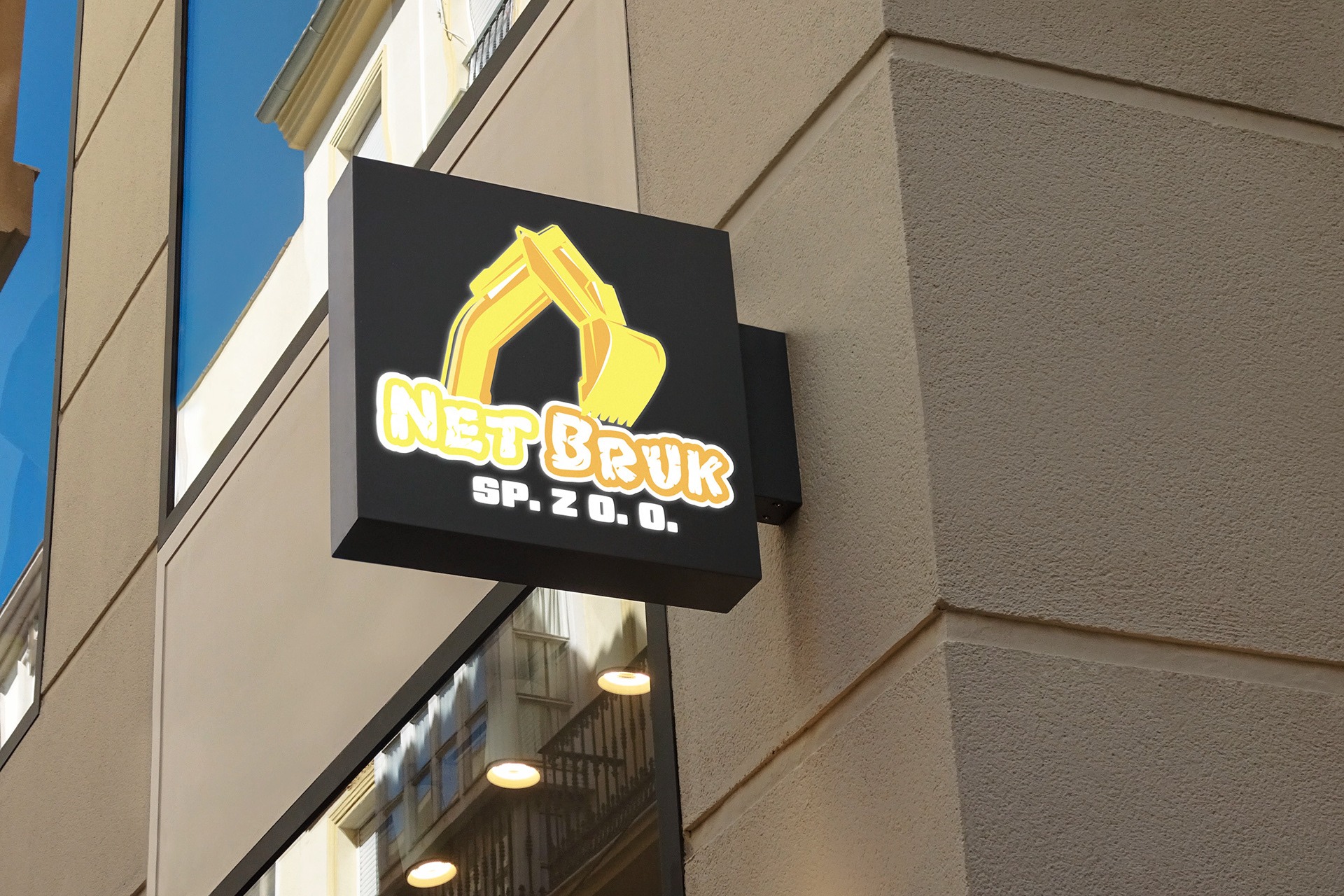 Kwadratowy szyld firmy 'NET BRUK SP. Z O.O.' z grafiką koparki na czarnym tle, przymocowany do elewacji budynku.