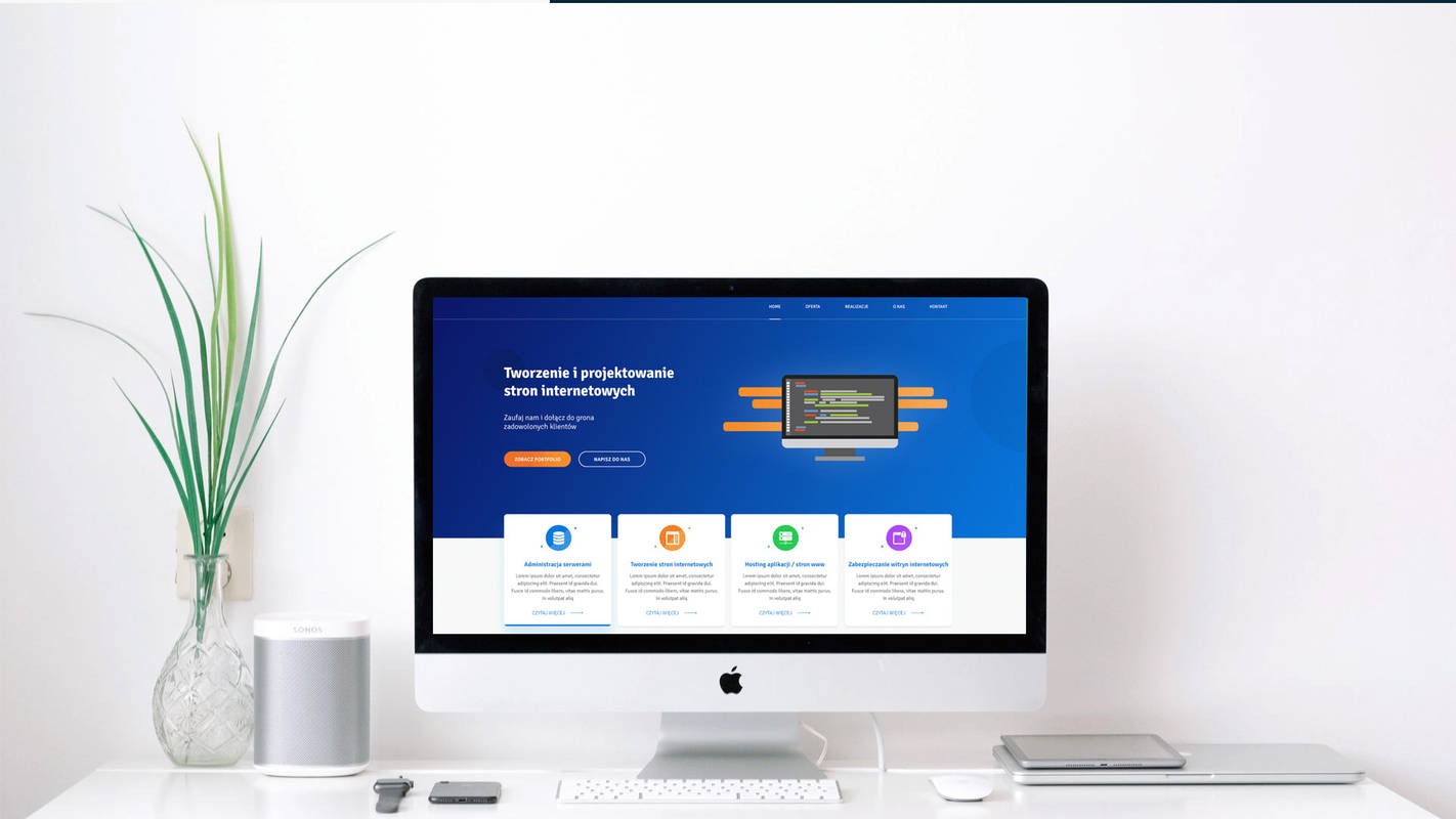 Ekran komputera iMac prezentujący stronę internetową z niebieskim motywem, obok wazon z zielonymi roślinami, głośnik Sonos i akcesoria Apple na białym biurku.