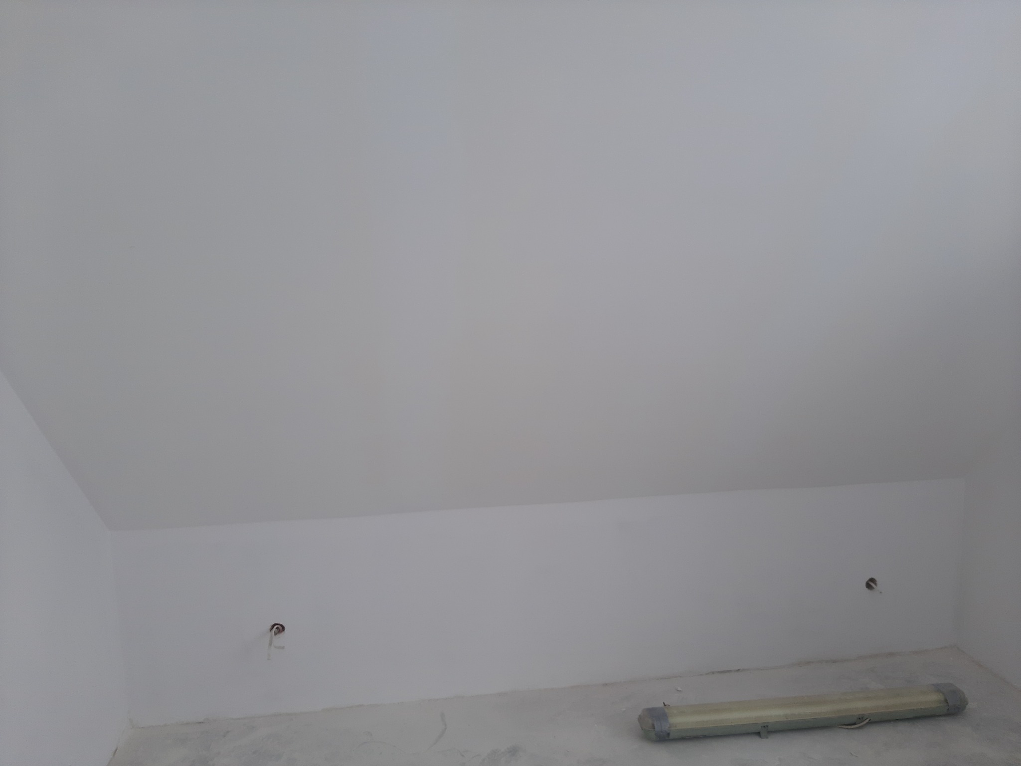 Poddasze po malowaniu na biało, widoczne gniazdka elektryczne i lampa podłogowa