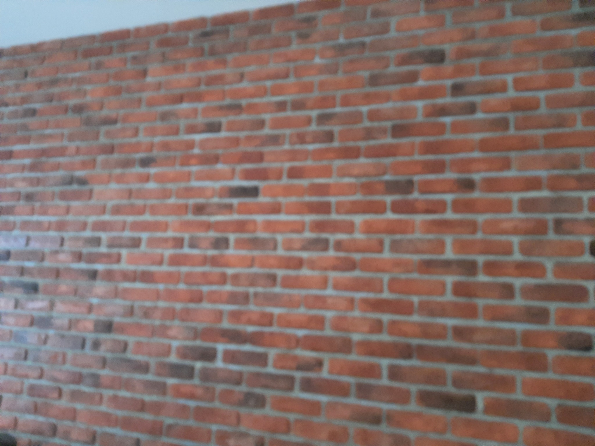 Ściana z czerwonej cegły klinkierowej z szarą fugą, imitacja starego muru, widok z boku.