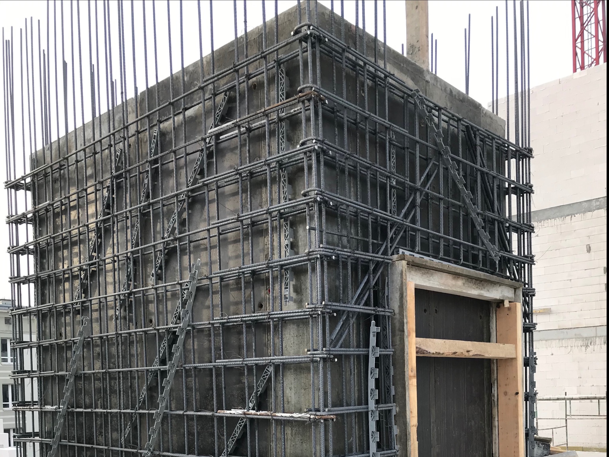 Szkielet zbrojenia ściany żelbetowej z widocznymi dystansami z tworzywa sztucznego i deskowaniem otworu okiennego.