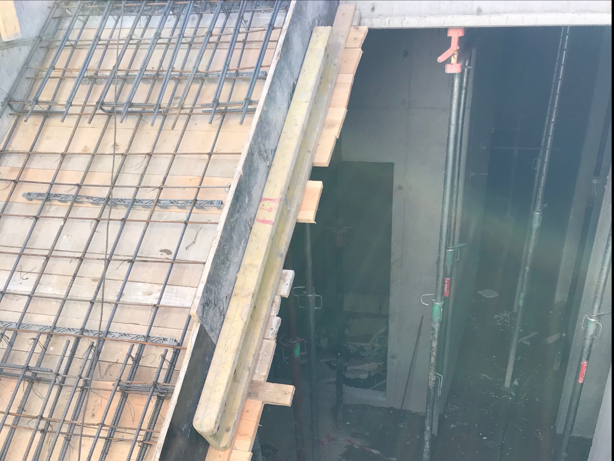 Zbrojenie fundamentu z drewnianym szalunkiem i metalowymi podporami wewnątrz wykopu.