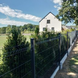 Hermes ogrodzenia - Nowoczesne ogrodzenie panelowe z podmurówką betonową i metalowymi słupkami na tle domu z ogrodem