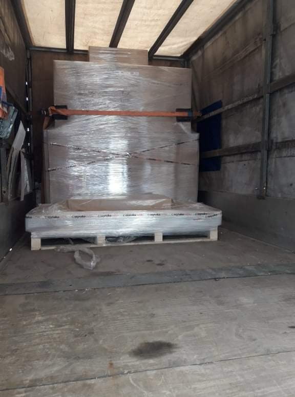 Wnętrze busa transportowego z zabezpieczonymi folią stretch paletami z towarem, przymocowanymi pasami transportowymi.