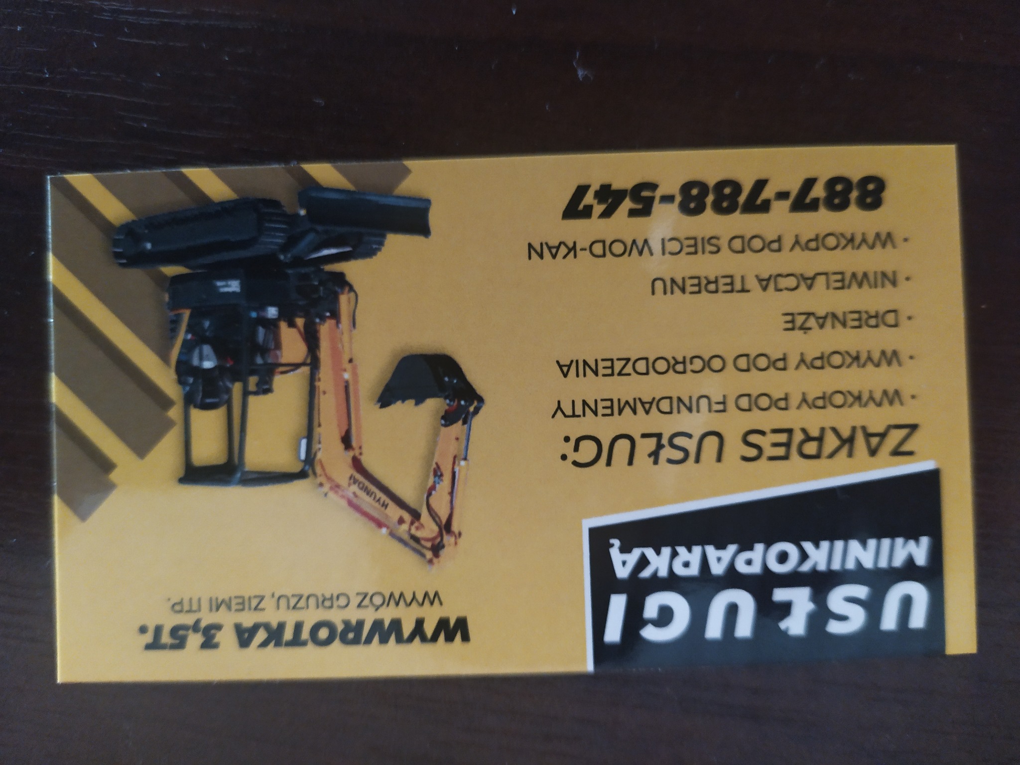 Wizytówka firmy oferującej usługi minikoparką, prezentująca zakres usług: wykopy pod fundamenty, ogrodzenia, drenaże, niwelacja terenu, wykopy pod sieci wod-kan, wywóz gruzu i ziemi.