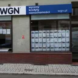 Fasada biura WGN z witrynami pełnymi ofert nieruchomości i szyldem informującym o wycenie kredyt&oacute;w i nieruchomości.