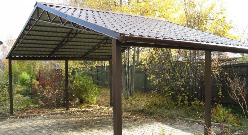 Zadaszenie tarasowe z metalową konstrukcją i brązową dachówką, widoczne z zewnątrz na tle jesiennej roślinności.