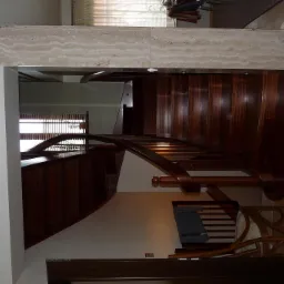 Eleganckie, drewniane schody z giętą balustradą i marmurowym wykończeniem, widok z góry na dół.