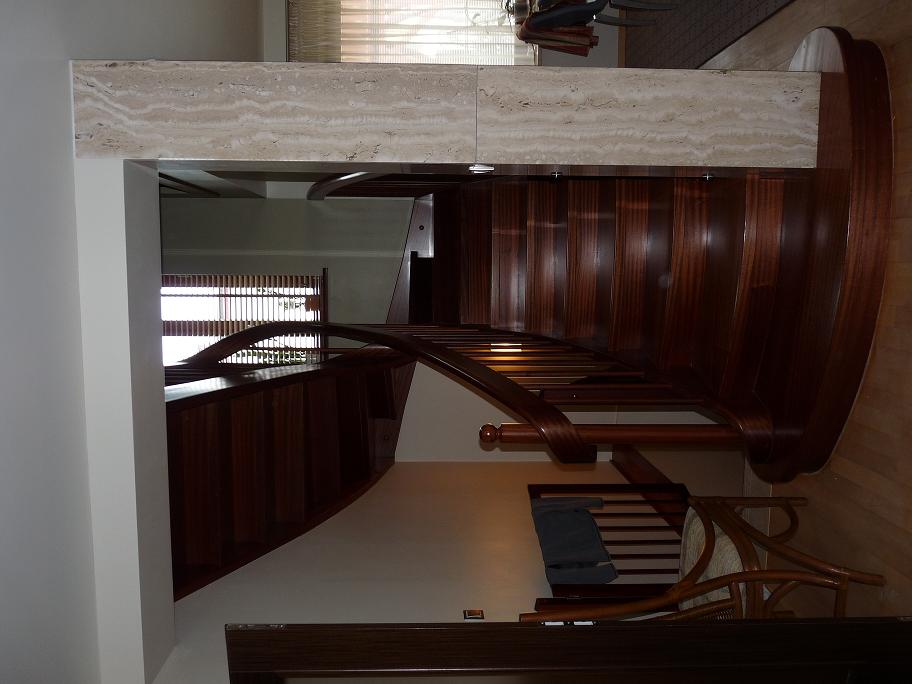 Eleganckie, drewniane schody z giętą balustradą i marmurowym wykończeniem, widok z góry na dół.