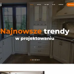 Strona internetowa pracowni mebli Drewland prezentująca aranżację kuchni w stylu klasycznym z białymi szafkami, czarnym blatem i okapem SMEG.