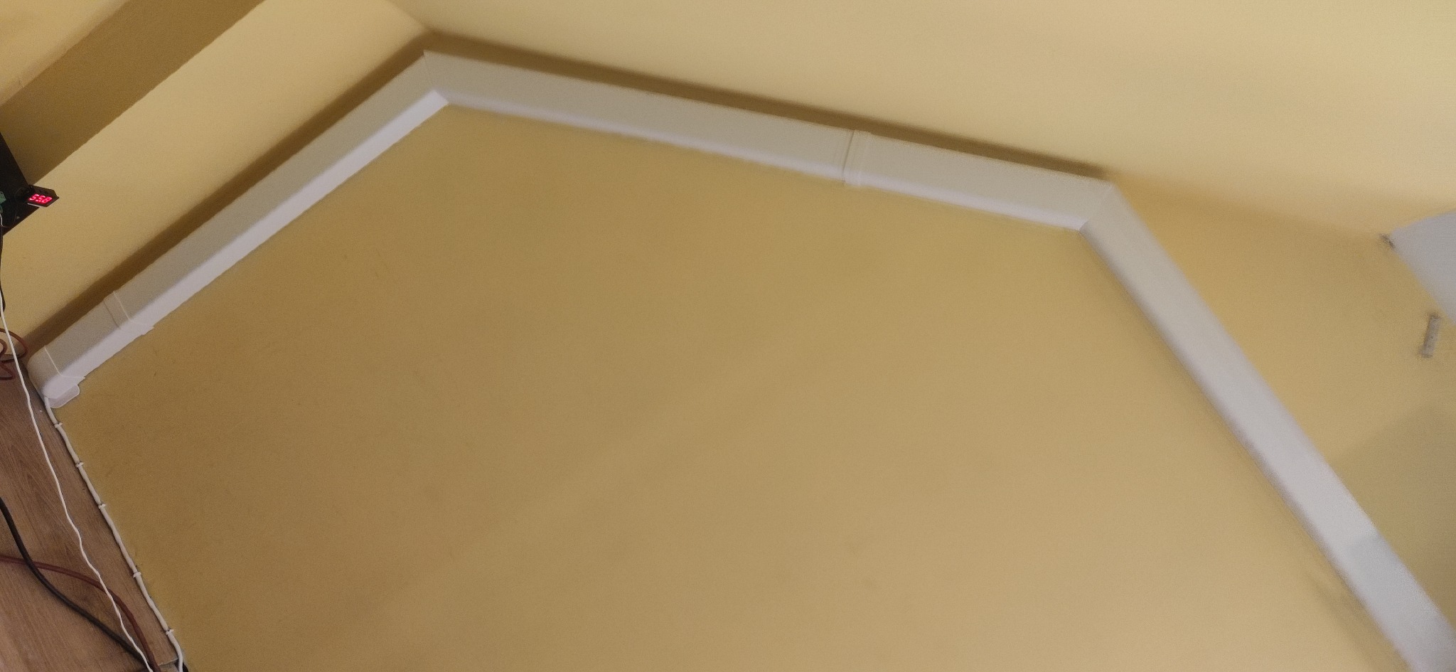 Białe kanały wentylacyjne ułożone pod kątem na żółtej ścianie, widoczne łączenia segmentów.