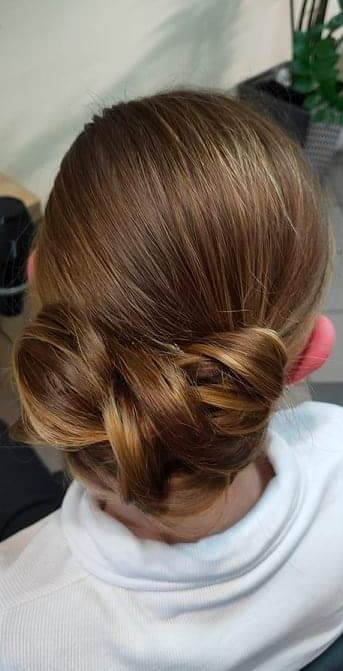 Upięcie włosów w niski kok z widocznymi refleksami, wykonane na włosach brąz z blond pasemkami, widok z tyłu.
