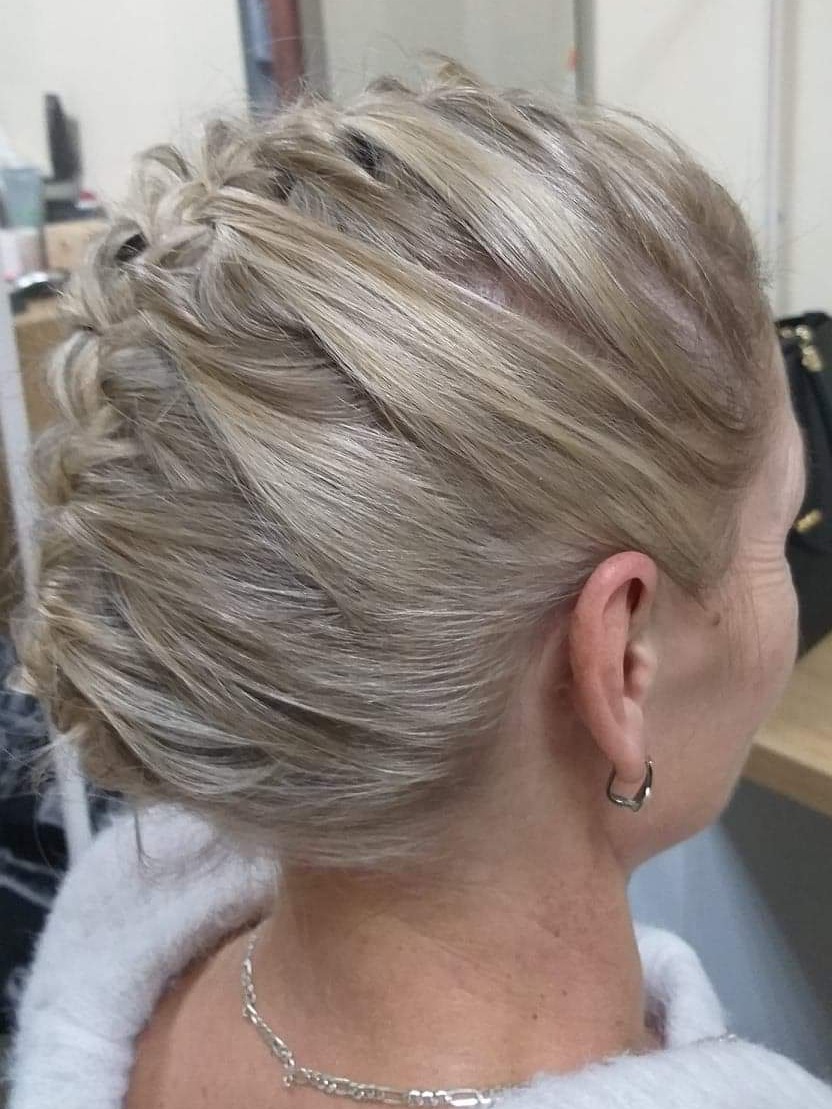 Blond włosy upięte w kok z warkoczem, widok z boku na tył głowy, srebrny łańcuszek na szyi i kolczyk w uchu.