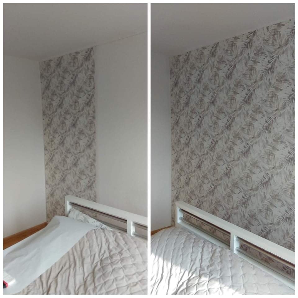 Fragment pokoju z tapetą w roślinny wzór, widok na ścianę nad łóżkiem, gdzie część ściany jest biała, a część pokryta tapetą w odcieniach szarości i beżu.